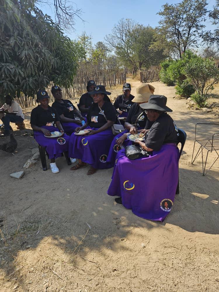 Outreach volunteers sharing a community meal under the trees